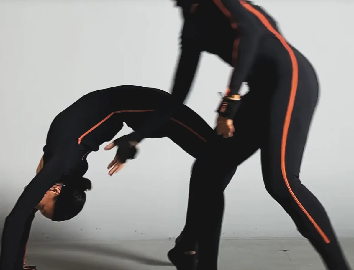 Deux corps en combinaison de motion capture enlacés dans un mouvement au sol